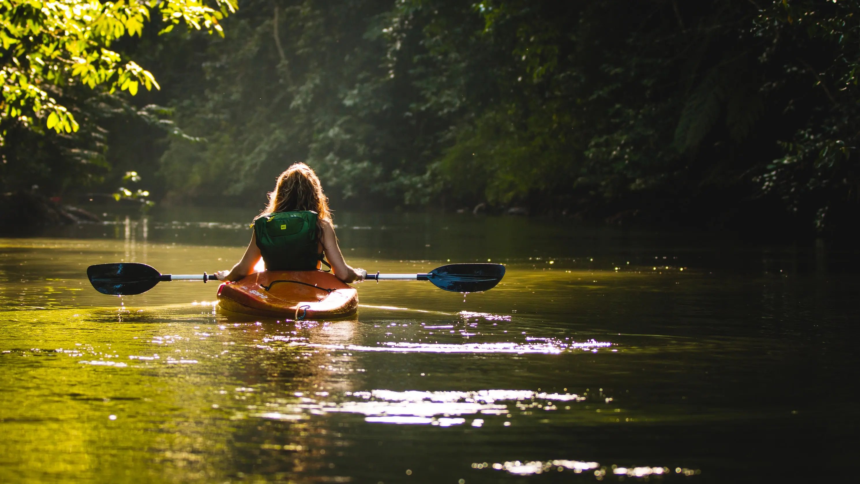 Girl kayaking down creek